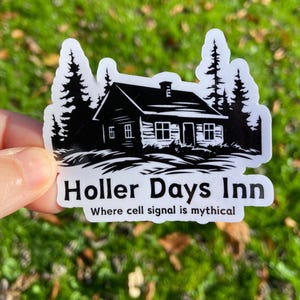 May include: Black and white sticker of a cabin in the woods with the text "Holler Days Inn" and "Where cell signal is mythical".