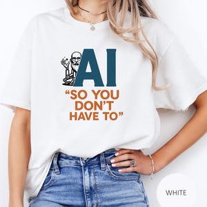 Könnte beinhalten: Weißes T-Shirt mit einem Grafikdesign mit den Buchstaben "AI" in Dunkelblau, einem Cartoon-Bild eines Mannes mit Brille und Bart und dem Text "SO YOU DON'T HAVE TO" in Orange.