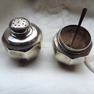 Puede incluir: Dos saleros y pimenteros de plata con un diseño facetado. Los saleros tienen una pequeña cuchara en el interior.