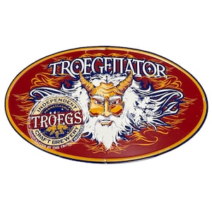 Peut inclure: Panneau métallique ovale avec un fond rouge et une bordure dorée. Le panneau présente une figure cornue et barbue avec le texte "TROEGENATOR" en haut et "TRÖEGS CRAFT BREWERY" en bas. Le panneau est un article promotionnel pour une brasserie.
