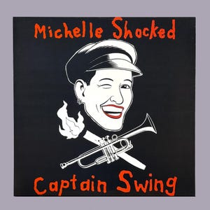 May include: Black square art print featuring a winking cartoon figure wearing a cap, with a trumpet and flames. The words "Michelle Shocked" and "Captain Swing" are written in orange, stylized lettering.