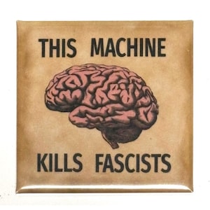 Op de afbeelding: Een vierkante button met een beige achtergrond en een centrale illustratie van een roze-bruin menselijk brein. De tekst "THIS MACHINE" staat in het zwart boven het brein en "KILLS FASCISTS" staat in het zwart onder het brein.
