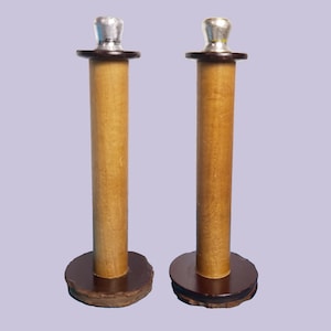 Könnte beinhalten: Zwei Kerzenhalter aus Holz mit silbernen Oberteilen und braunen Sockeln. Die Kerzenhalter sind etwa 25 cm hoch.