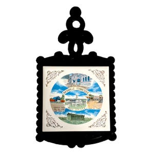 May include: Black trivet with a decorative frame and a central tile featuring images of Nashville, Tennessee landmarks. The tile includes text that reads "Nashville Tennessee", "Music City USA", and "Frontier Town".