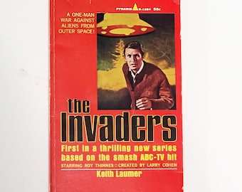 May include: A red paperback book cover with a black and white illustration of a flying saucer and a man running. The title of the book is "The Invaders" and the text reads "First in a thrilling new series based on the smash ABC-TV hit starring Roy Thinnes created by Larry Cohen Keith Laumer."