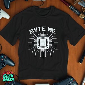 以下が含まれることがあります： コンピュータチップと「BYTE ME」というテキストの白いグラフィックが描かれた黒いTシャツ。