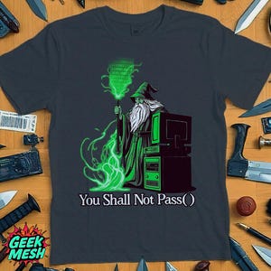 May include: A dark blue t-shirt with a green and white illustration of a wizard holding a staff with binary code. The wizard is standing in front of a computer tower. The text "You Shall Not Pass()" is printed below the illustration.