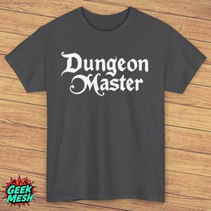 Puede incluir: Una camiseta gris oscuro con el texto "Dungeon Master" en blanco, en letras estilizadas.