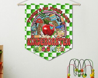 Pode incluir: Uma decoração de parede com um fundo xadrez verde e branco. O design apresenta uma maçã vermelha, material escolar e o texto "THERE'S NO PLACE LIKE KINDERGARTEN MRS. SMITH."