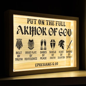 May include: A wooden light-up sign with the text "PUT ON THE FULL ARMOR OF GOD" and a graphic of the armour of God with the text "BELT OF TRUTH, BREAST PLATE OF RIGHTEOUSNESS, SHOES OF PEACE, SHIELD OF FAITH, HELMET OF SALVATION, SWORD OF SPIRIT" and the text "EPHESIANS 6:10".