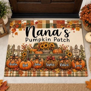 May include: A rectangular doormat featuring a plaid border and a central illustration of a vintage truck filled with sunflowers and pumpkins. The text reads Nana's Pumpkin Patch and Fresh Pumpkins 25c. Six pumpkins are personalized with names.