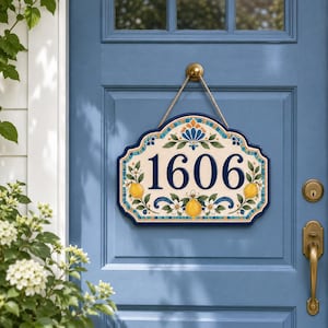 May include: A decorative address sign with the number 1606 in navy blue. The sign has a cream background with lemon and floral accents. The border is navy blue, and the sign hangs from a natural rope.