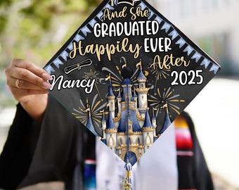以下が含まれることがあります： 卒業帽。ディズニーのお城のデザインと「And She Graduated Happily Ever After 2025」の文字、そして「Nancy」の名前入り。黒色の帽子に金と青のアクセント、タッセルが付いています。