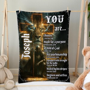 May include: A black blanket featuring a lion's face within a cross design, with the name "Joseph" and uplifting text. The text includes phrases such as "chosen," "made for a purpose," and "a child of God."