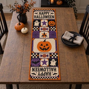 May include: A rectangular quilted table runner featuring a repeating Halloween theme with orange, purple, black, and white colours. The design includes jack-o'-lanterns, ghosts, bats, stars, candy, and the text HAPPY HALLOWEEN in black lettering.