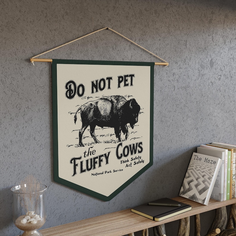 May include: A green and white sign with the text "DO NOT PET the FLUFFY COWS" and a black and white illustration of a bison. The sign also includes the text "Think Safety Act Safely" and "National Park Service".