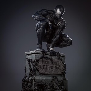 May include: Black and white statue of Venom, a Marvel Comics superhero, crouching on a tombstone that reads "Here Lies Eddie Brock".