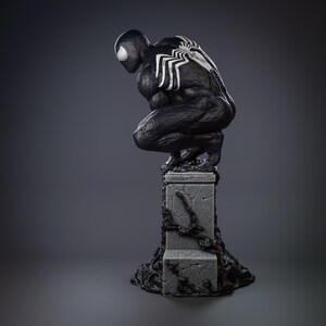 May include: Black and white figurine of Venom, a Marvel Comics superhero, crouching on a stone base with black vines. The figurine is detailed with a textured surface and white spider-like markings.
