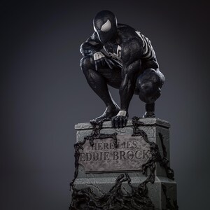 May include: A black and white statue of Venom, a Marvel Comics superhero, crouching on a tombstone. The tombstone reads "Here Lies Eddie Brock".