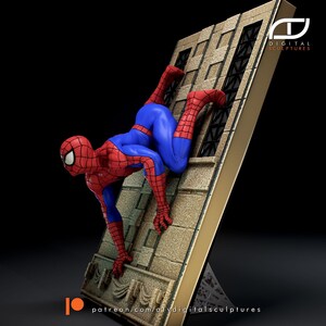 May include: A red and blue Spider-Man action figure is climbing a building. The figure is posed in a dynamic action pose with one leg extended and the other bent. The figure is holding onto the building with its hands. The building is made of a light brown material and has windows. The figure is set against a black background.