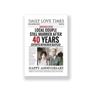 Op de afbeelding: Een nieuwigheidskrantenprint getiteld DAILY LOVE TIMES met de kop LOCAL COUPLE STILL MARRIED AFTER 40 YEARS. Het bevat een vintage zwart-witfoto van een koppel en de tekst HAPPY ANNIVERSARY en HERE'S TO THE NEXT CHAPTER OF OUR LOVE STORY.