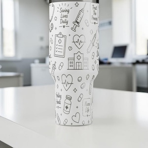 Puede incluir: Un vaso blanco con un dise&ntilde;o de arte lineal negro con s&iacute;mbolos m&eacute;dicos y el texto "Saving Lives Daily" y "Trust The Process". El dise&ntilde;o incluye estetoscopios, jeringas, corazones y frascos de pastillas.