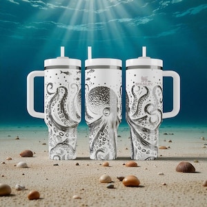May include: Three white insulated tumblers with black octopus illustrations and white handles. Each tumbler has a white lid and a straw. The tumblers are on a sandy surface with seashells and pebbles, with an underwater background.