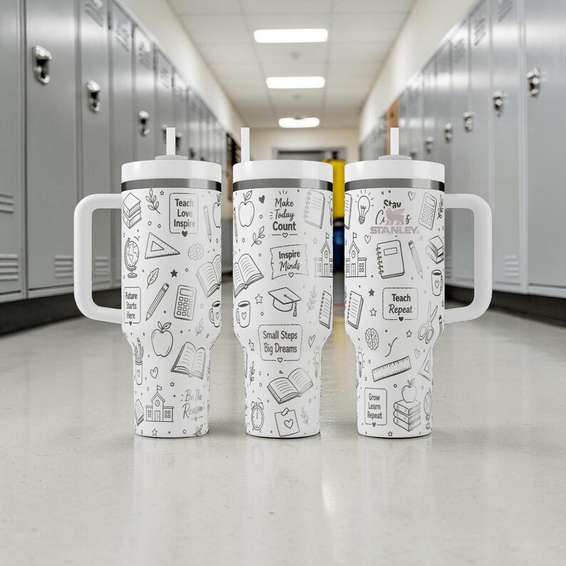 May include: Three white Stanley tumblers with black line art of school-related icons and text. Each tumbler has a white handle and lid with a straw. The text includes "Teach Love Inspire", "Make Today Count", and "Teach Repeat".
