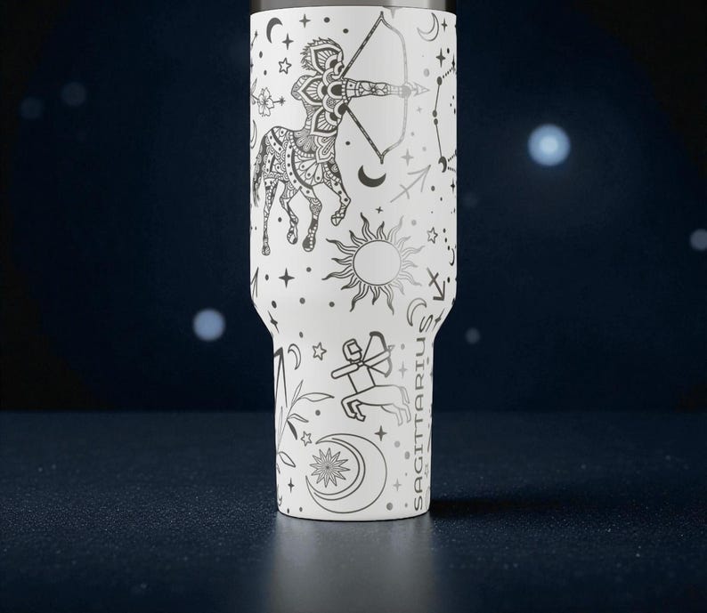 Op de afbeelding: Witte beker met een zwart Boogschutter dierenriem ontwerp. Het ontwerp bevat een centaur boogschutter, sterrenbeelden, zon, maan en sterren. Het woord "SAGITTARIUS" staat verticaal op de zijkant.