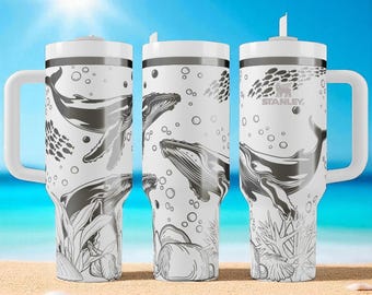 May include: Three white Stanley tumblers with handles and straws, featuring a black and white line art pattern of humpback whales, schools of fish, bubbles, coral, and seashells. The Stanley logo is printed on the rightmost tumbler.