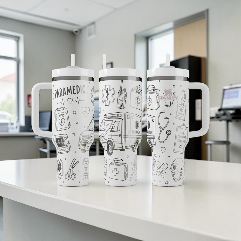 May include: Three white insulated tumblers with black line art illustrations of paramedic symbols, including an ambulance, AED, and stethoscope. Each tumbler has a white handle and lid with a straw. The text "PARAMEDIC" is on one tumbler.
