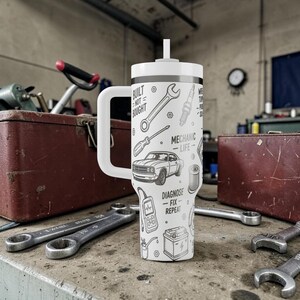 May include: White travel mug with a handle and a straw, featuring a black and white mechanic-themed design. The design includes tools, a car, and the text "Built Not Bought" and "Mechanic Life - Diagnose - Fix - Repeat."
