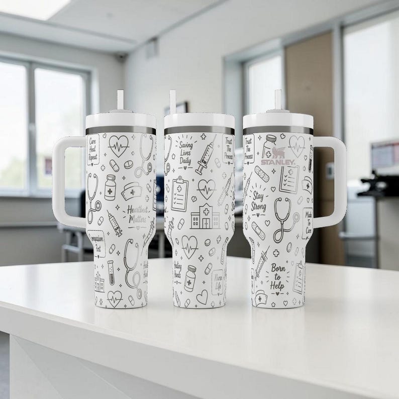 Puede incluir: Tres vasos aislados blancos con dibujos lineales negros de s&iacute;mbolos m&eacute;dicos, corazones y texto. Cada vaso tiene un asa, tapa y pajita blancos. El texto incluye "Heartbeat Matters", "Saving Lives Daily", "Stay Strong" y "Born to Help".