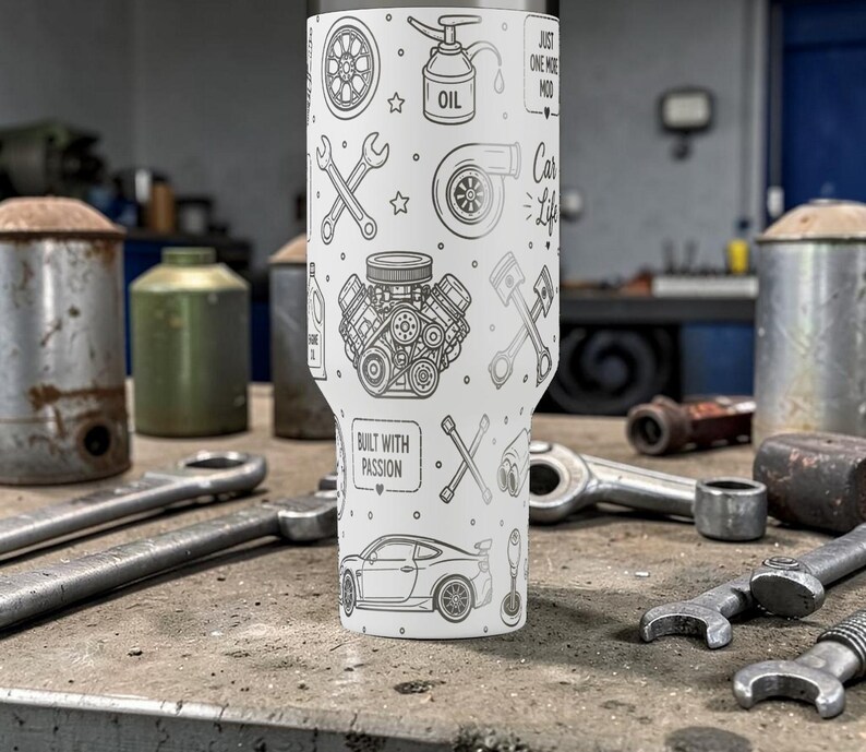 Op de afbeelding: Een witte tumbler met een autothema, versierd met auto-gerelateerde illustraties. Het ontwerp bevat afbeeldingen van automotoren, zuigers en sleutels. De tekst "Built with Passion" en "Just One More Mod" zijn ook zichtbaar.