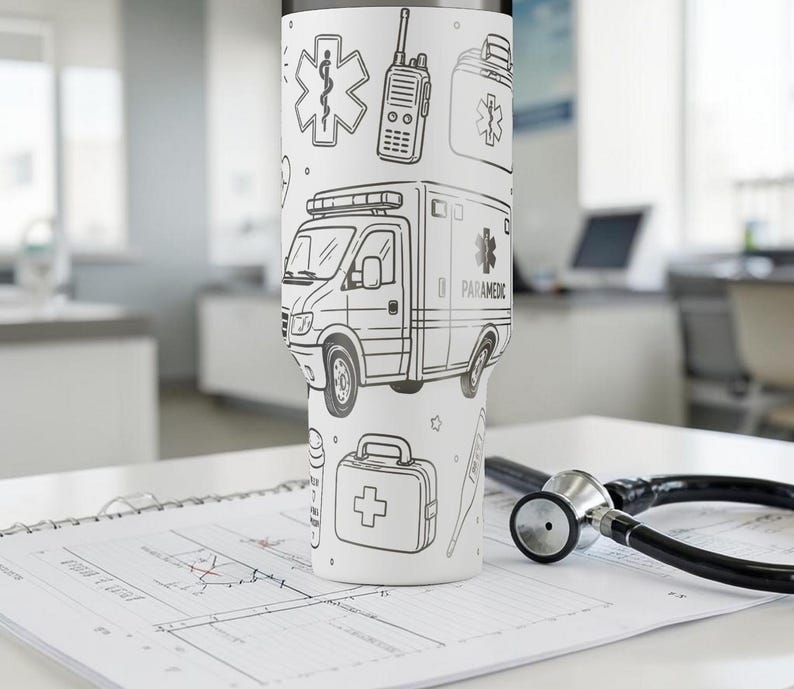 May include: A white tumbler featuring black line drawings of medical symbols, an ambulance, and a first aid kit. The tumbler is on a table with a stethoscope and medical paperwork.