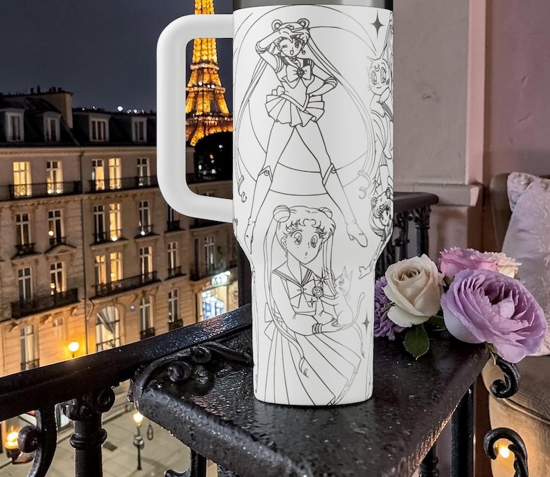 May include: White tumbler with a large handle, featuring a detailed black and white illustration of anime characters. The design includes multiple figures in various poses. The background shows a city at night.