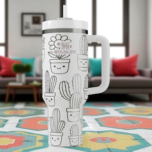 Puede incluir: Un vaso Stanley blanco con asa y tapa. El vaso está decorado con un patrón repetido de cactus sonrientes y flores en macetas en blanco y negro. El logotipo de Stanley es visible.