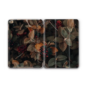 May include: An open tablet case featuring a nature-themed design. The case displays a close-up of a plant with brown and green leaves, and clusters of red and dark blue berries. The overall aesthetic is dark and moody.