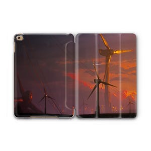 Könnte beinhalten: Eine iPad-Hülle mit einer Sonnenuntergangsszene mit Windkraftanlagen. Das Bild zeigt ein Feld von Windkraftanlagen vor einem orange-violetten Himmel. Die Hülle ist geöffnet und zeigt das Kunstwerk.