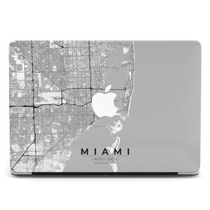 May include: A gray laptop skin featuring a detailed map of Miami, Florida, with the Apple logo and the city's name in black text. The words "United States" and coordinates are also visible. The design is a grayscale topographic representation.