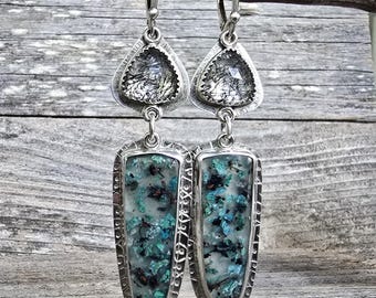 Puede incluir: Pendientes de plata con una parte superior triangular y una inferior rectangular. La sección superior presenta una piedra transparente con inclusiones negras, mientras que la inferior tiene un diseño moteado turquesa y negro.