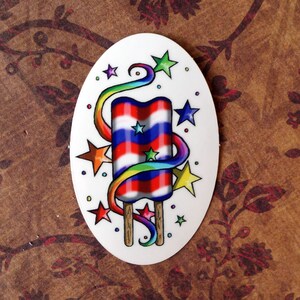 May include: A white oval sticker with a red, white, and blue popsicle with a rainbow swirl around it. There are yellow, blue, and red stars around the popsicle.