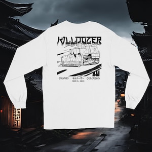 Może przedstawiać: Biały t-shirt z długim rękawem z czarno-białą ilustracją buldożera. Tekst "BULLDOZER" jest napisany japońskimi znakami nad buldożerem. Tekst "Granby Bulldozer Colorado June 4, 2004" jest napisany pod buldożerem.