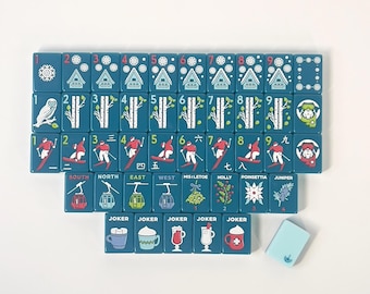 May include: A set of teal mahjong tiles featuring winter-themed illustrations including snowflakes, cabins, owls, birch trees, skiers, ski lifts, plants, and mugs labeled JOKER. The tiles display numbers, Chinese characters, and English text.