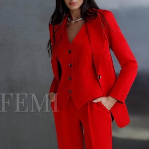 May include: A red suit comprising a blazer, waistcoat, and trousers. The suit has a classic, tailored fit.