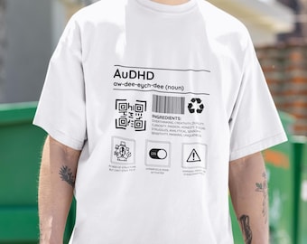 May include: White t-shirt with a black graphic design that reads "AUDHD aw-dee-eych-dee (noun)" and includes a QR code, a list of "ingredients", and three icons. The icons are labeled "In need of structure but can't stick to it", "Hyperfocus mode activated", and "Warning: May experience overthinking and anxiety".