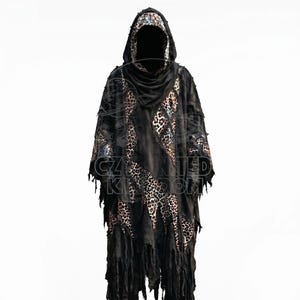 May include: A hooded poncho featuring a patchwork design of black fabric and leopard print panels. The garment has a distressed aesthetic with frayed, uneven edges and long, hanging strips of fabric along the hemline and sleeves.