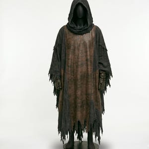 May include: A dark costume with a hooded cloak and tattered edges. The cloak is primarily black with a brown leather-like panel down the front. The costume includes gloves and is displayed on a mannequin.