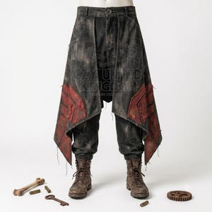 Puede incluir: Pantalones gris oscuro desgastados con una sobre-falda asimétrica superpuesta, bordes deshilachados y parches geométricos rojos. La prenda incluye cierre de botón y se combina con botas marrones con cordones. Un hueso, una llave y un engranaje.