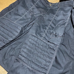 May include: Black pants with white stitching and a cargo pocket. The pants have a quilted design on the front and the text "CZY UNITED KINGDOM" printed on the front. The pants are made of a durable material.